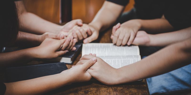 A group of students or educators standing together in unity, perhaps in front of a cross or Bible