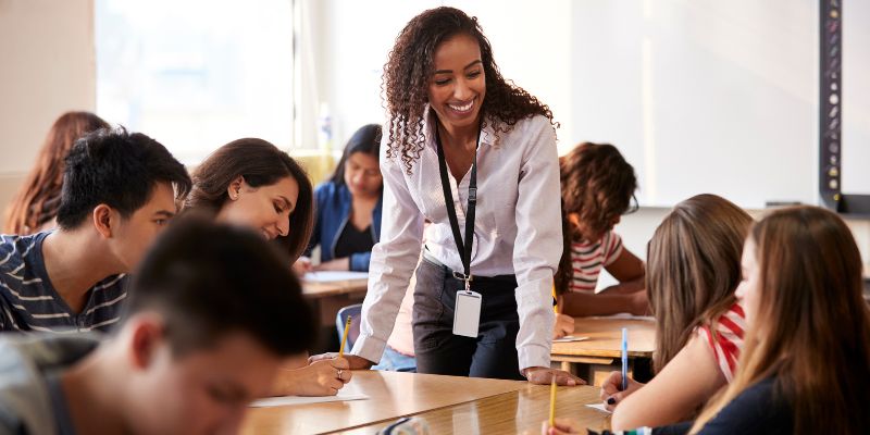 A teacher addressing misconceptions in a classroom setting with students actively engaged in conversation or asking questions.