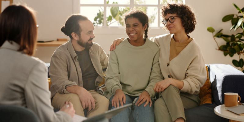 An educator talking with parents or a group of students, possibly in a mentoring scenario.